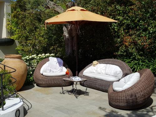 two wicker chairs and a table with an umbrella at Hotel Orsa Maggiore in Anacapri