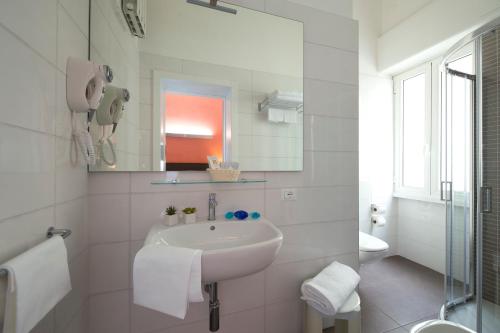 a white bathroom with a sink and a mirror at Hotel Giulia in Lido di Camaiore