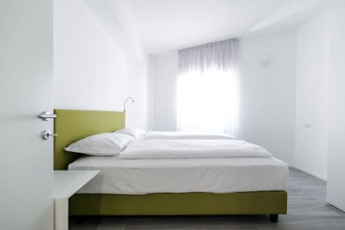 a bed in a white room with a window at Bertamini Apartments in Nago-Torbole