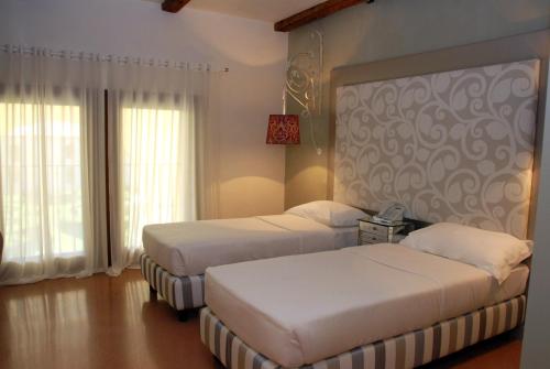 two beds in a hotel room with windows at Villa Foscarini Cornaro in Gorgo al Monticano