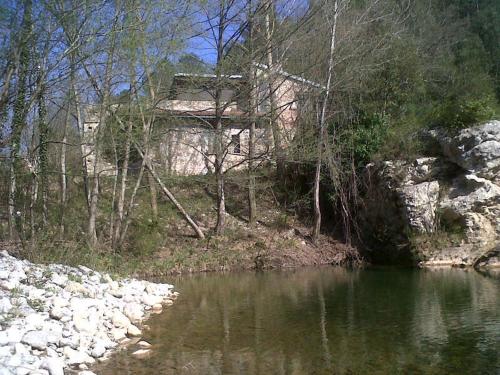 a building sitting on the side of a river at La Farga de la Muga in Sant Llorenç de la Muga