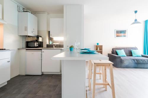 a kitchen and living room with white cabinets and a stool at Ombre Bleue in Toulouse