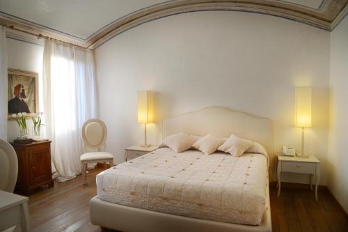 a bedroom with a white bed with two tables and two lamps at Villa Foscarini Cornaro in Gorgo al Monticano