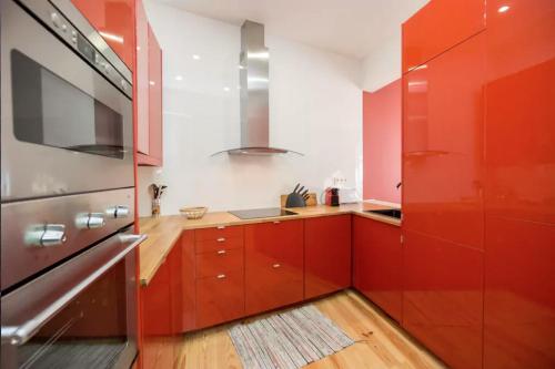 リスボンにあるLD Chiado - Super Central - ACのキッチン(赤いキャビネット、ステンレス製の冷蔵庫付)