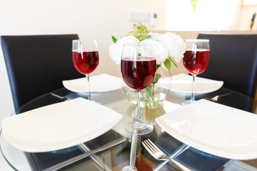 a table with three glasses of red wine and white flowers at Wordsworth Apartment Irene court in Cockermouth