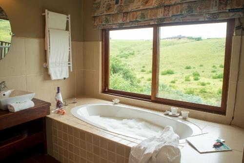 a bath tub in a bathroom with a window at Granny Mouse Country House & Spa in Balgowan