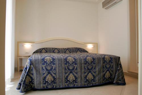 ein Schlafzimmer mit einem Bett mit einer blauen Decke darauf in der Unterkunft Residence Olimpo in Rimini