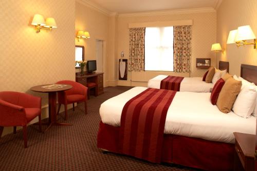 a hotel room with two beds and a table and chairs at The Midland Hotel in Bradford