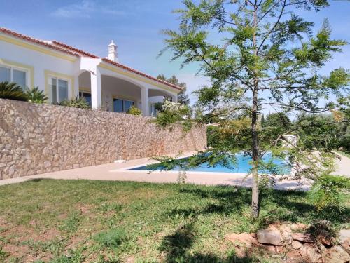 a house with a stone wall and a tree at Casa do Monte in Silves