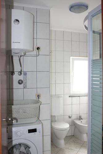 a bathroom with a washing machine and a toilet at Turković Apartments in Žgaljić