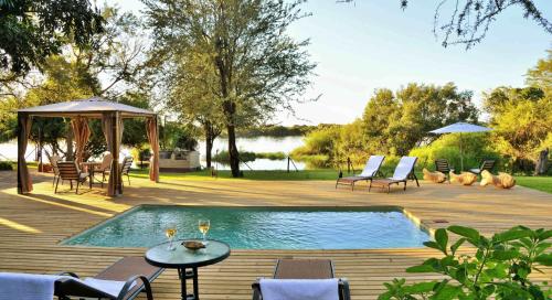 a swimming pool on a deck with chairs and a table at River View Lodge in Kasane