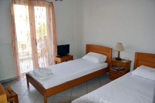 a bedroom with two beds and a tv and a window at Iliaktida Studios in Vasiliki
