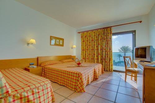 Cette chambre comprend deux lits et une télévision. dans l'établissement SBH Club Paraiso Playa, à Playa Jandía