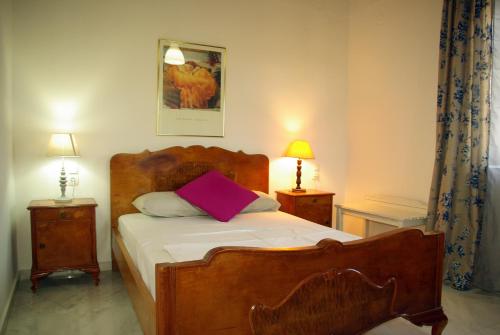 - une chambre avec un lit en bois et un oreiller violet dans l'établissement Villa Vigles, à Vóroi