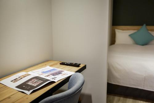 a room with a table with a newspaper and a bed at Hub Hotel Zhongli in Zhongli