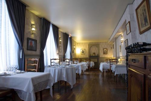 a dining room with tables with white tablecloths at Hôtel De La Banniere De France in Laon