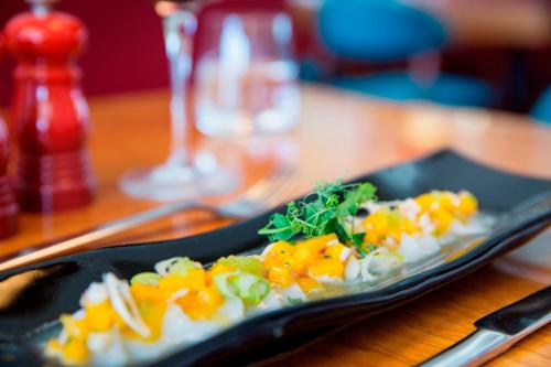 a black plate of food on a wooden table at Hotel Esplendido in Port de Soller