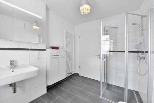 een witte badkamer met een wastafel en een douche bij Ferienwohnung Morgenrot in Juliusruh