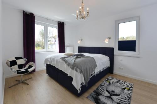 a bedroom with a bed and a chair and windows at Ferienwohnung Morgenrot in Juliusruh