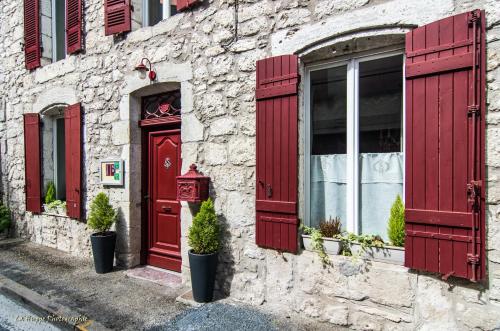 um edifício com persianas vermelhas e uma porta vermelha em Maison Nº 20 em Eymet