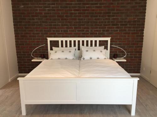 a white bed in a room with a brick wall at Das kleine Stadtapartment in Burg auf Fehmarn