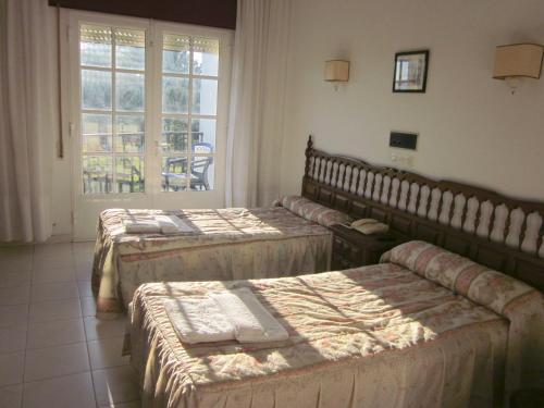 three beds in a room with a window at Hotel Sixto in Montalvo