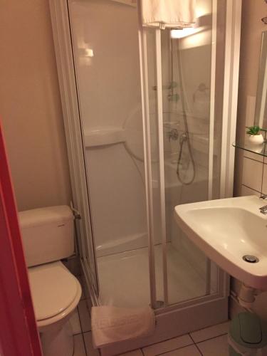 a bathroom with a shower and a toilet and a sink at Hôtel Le Bambi in Baume-les-Dames