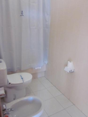 a white bathroom with a toilet and a sink at Hotel Sixto in Montalvo