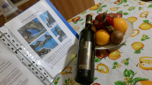 a bottle of wine and a bowl of fruit on a table at Villa Laura Apartment in Giardini Naxos