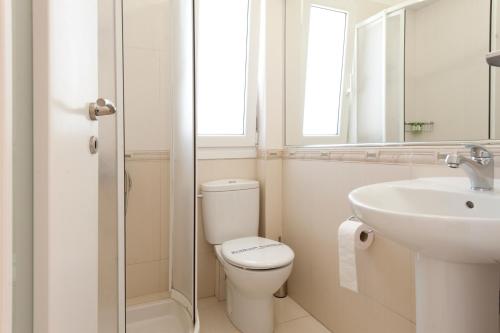 Un baño blanco con inodoro y lavabo. en Hotel Anezina, en Pylos