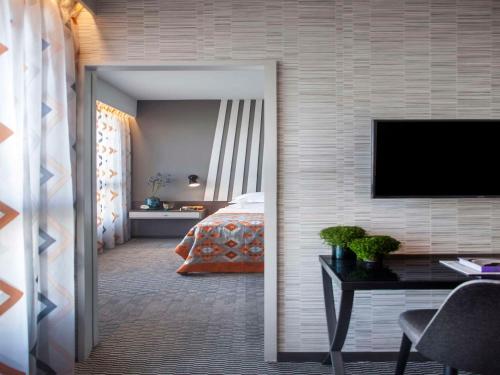 a bedroom with a bed and a desk with a television at Dan Panorama Haifa Hotel in Haifa