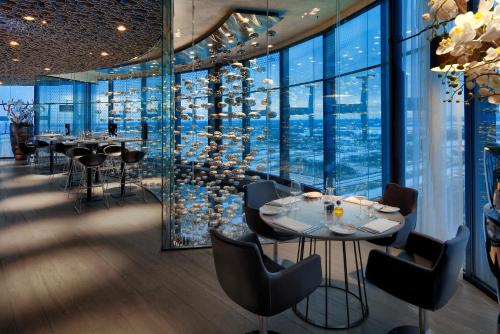 un restaurante con mesas, sillas y ventanas grandes en Fletcher Hotel Amsterdam, en Ámsterdam