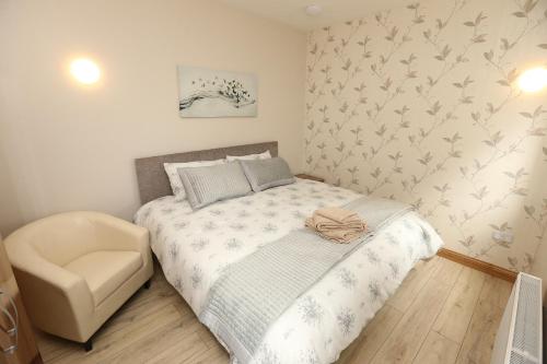 a small bedroom with a bed and a chair at Pebble Beach Holiday Home in Ballinphull
