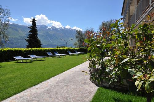 a row of benches in a park with mountains in the background at Hotel Rosemarie in Limone sul Garda