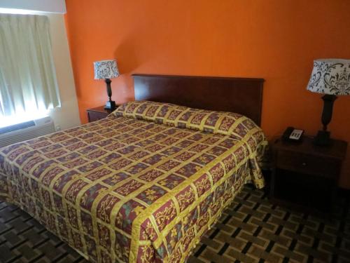 a bedroom with a bed with an orange wall at Budget Inn in Cocoa