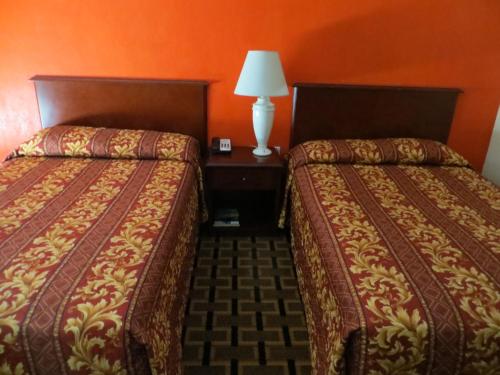 two beds in a hotel room with orange walls at Budget Inn in Cocoa