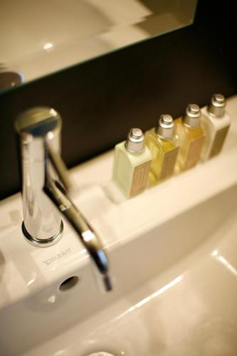 - un lavabo dans la salle de bains avec 3 bouteilles de savon dans l'établissement Les 4 étoiles, à Montpellier