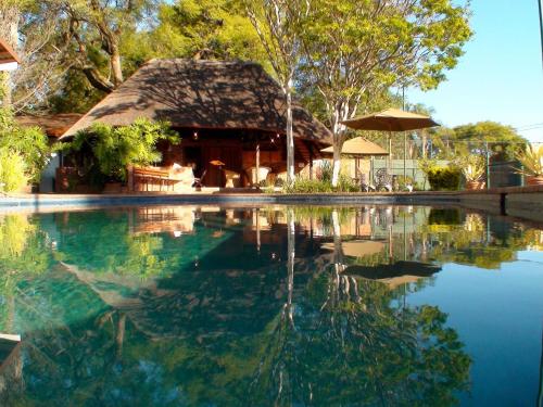a house with a pool of water with a thatch roof at Polokwane Place in Polokwane