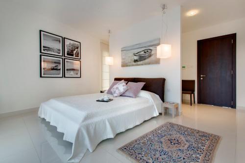 ein weißes Schlafzimmer mit einem Bett und einer braunen Tür in der Unterkunft Marvellous Apartment in Tigne Point in Sliema