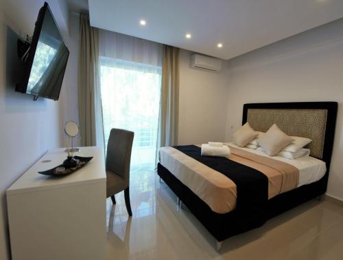 a bedroom with a bed and a desk and a television at Athena Apartment in Artemida