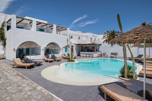 a swimming pool with chairs and umbrellas in a resort at Nissia Beach Apartments & Suites in Kamari