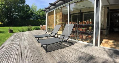 two chairs sitting on a deck next to a house at Chambre D'Hôtes le Phenix in Saint-Martin-du-Vivier