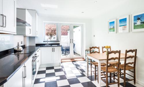 a kitchen with white cabinets and a table and chairs at Lobster Cottage Lytham in Lytham St Annes