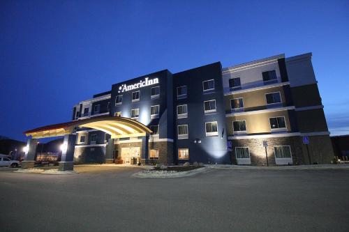 a hotel building with a lit up facade at night at AmericInn by Wyndham Winona in Winona