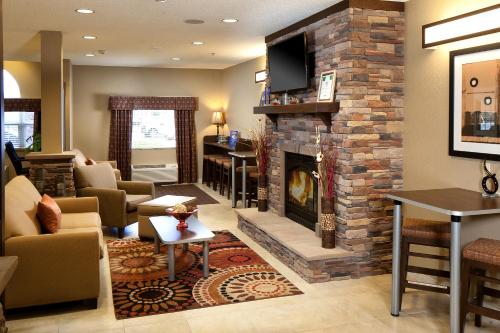 a living room with a stone fireplace with a tv at Microtel Inn & Suites by Wyndham Wheeling at The Highlands in Triadelphia