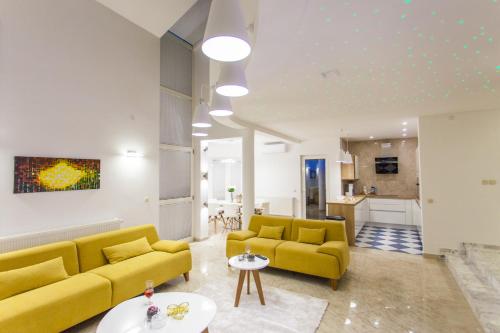 a living room with yellow couches and a kitchen at Villa Roza Murter in Murter