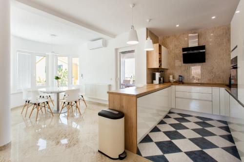 a kitchen with white cabinets and a table with chairs at Villa Roza Murter in Murter