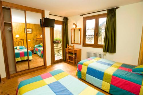 a hotel room with two beds and a balcony at Hotel Llibrada in Benasque