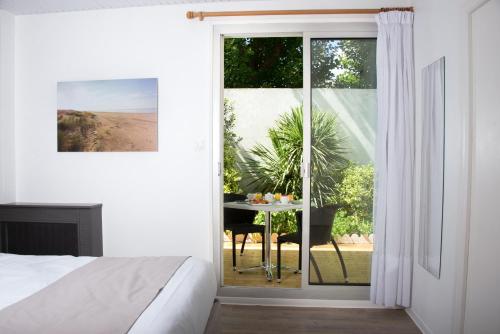a bedroom with a bed and a table outside a window at Hotel Les Dunes in La Tranche-sur-Mer