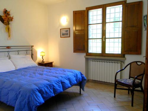 1 dormitorio con 1 cama azul y 1 silla en Appartamenti Avanella a 150 mt dalla piscina 150 mt from swimming pool, en Certaldo